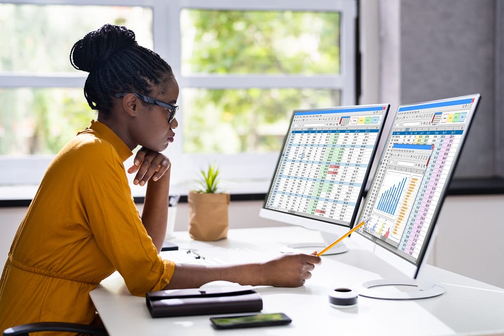 Woman analyzing data on dual monitors