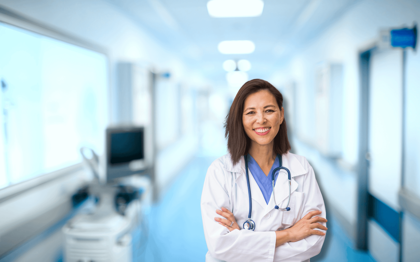 A confident doctor with a stethoscope stands with arms crossed in a bright hospital hallway, symbolizing healthcare professionalism.